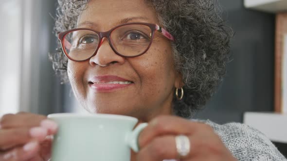 Senior mixed race woman enjoying drinking tea. Social distancing and self isolation in quarantine