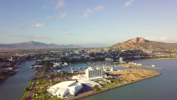 Drone over ocean moving slowly toward Townsville harbour and city on a sunny morning.