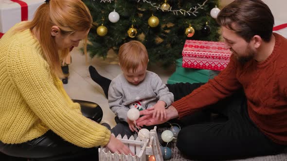 Happy family having fun and playing together near Christmas tree at home.