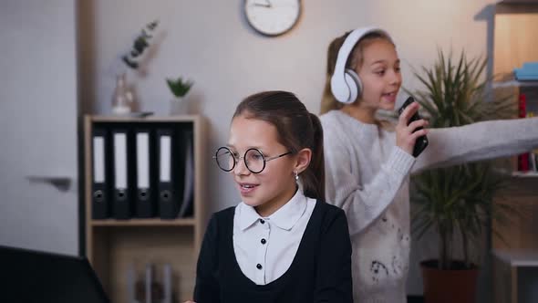 Schoolgirl in Glasses Showing Something Interesting to Her Older Sister that Dancing