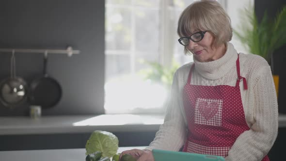 Cheerful Senior Woman Smelling Organic Delicious Avocado Tangerine and Apple Smiling