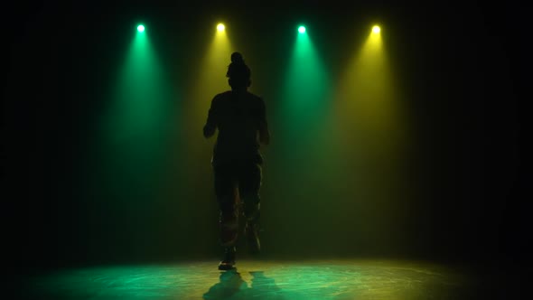 Silhouette Man Enjoying Hip Hop Moves in Dark Studio with Smoke. Green and Yellow Lighting. Slow