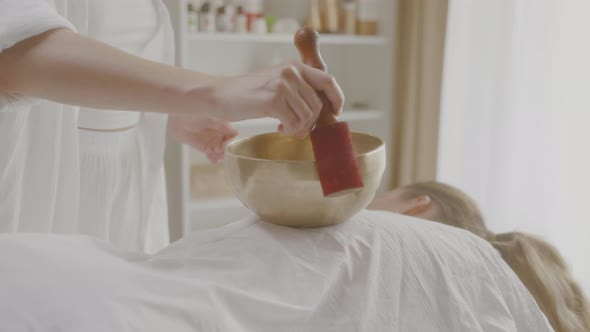 Masseuse Twists Stick Around Singing Bowl During Sound Therapy Session Spa