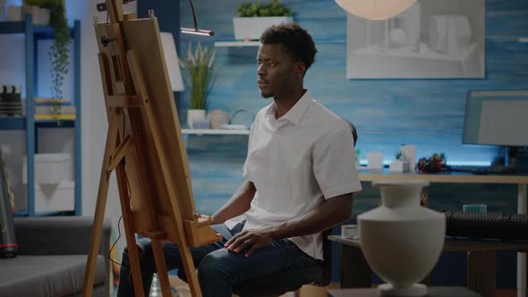 African American Person Sitting in Art Studio with Drawings