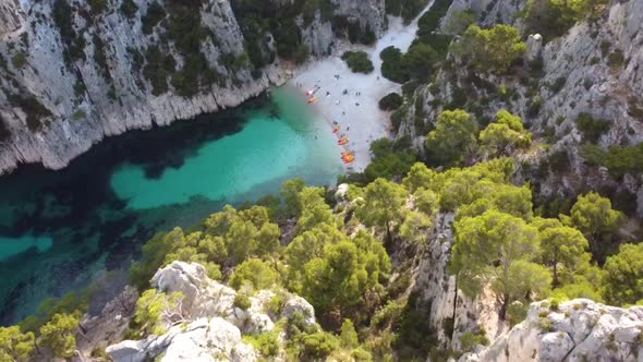 Flying down a cliff with focus on a stone beach with turquis water