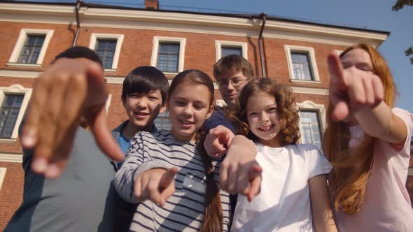 Portrait of Diverse Schoolkids Pointing at Camera and Laughing Outdoors