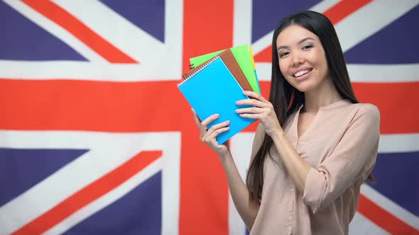 Pretty Female Student Showing Copybooks Against British Flag, Learning Language