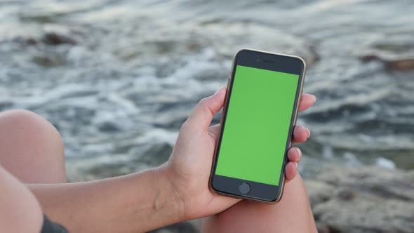 NICE, FRANCE - JULY 2017 Female holds green screen  gadget by the sea