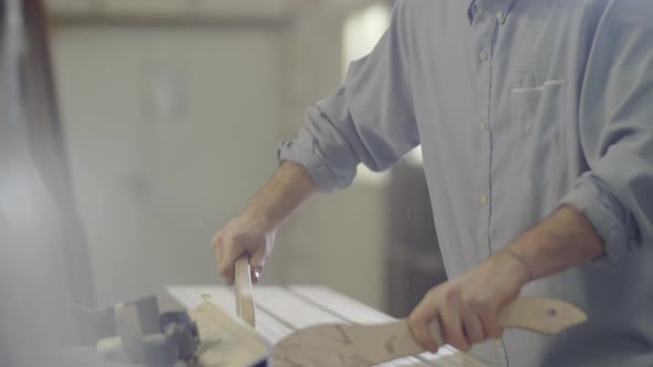 Caucasian Man in Goggles Cutting Piece of Wood on Table Saw at Workshop