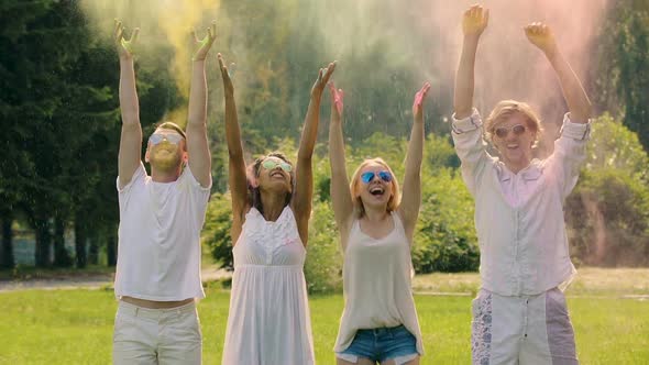 Happy Young People Throwing Colored Powder in Air Having Fun at Party Together