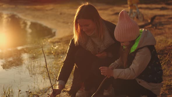 Mother and Daughter at Sunset in Slow Motion and Sunlight Talk and Play By the Water Together