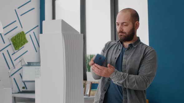 Close Up of Man Working on Architecture Project with Mobile Phone to Design Building Model