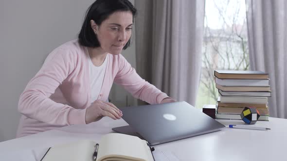 Portrait of Caucasian Woman Coming To Table, Looking Around and Opening Laptop. Young Mother or Wife