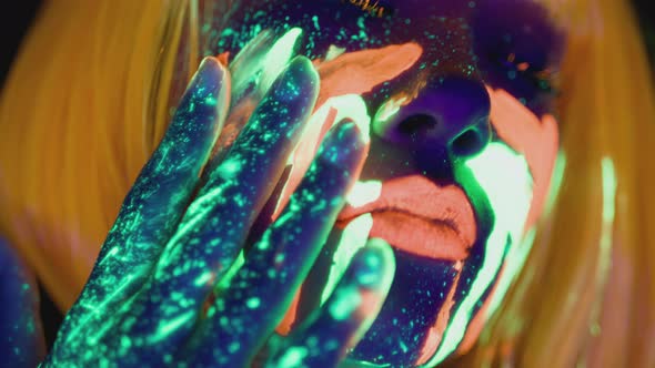 Extreme Close Up of Young Woman with Bright Neon Makeup Smearing Glowing Fluorescent Paint on Her