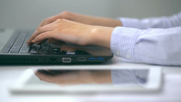 Female Hands Typing on a Laptop Keyboard in a White Office