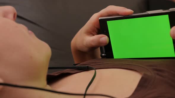 Headphones attached on smart phone in womans hands with green screen 4K 2160p UHD slow panning  foot