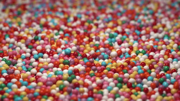 Close Up Macro Footage of Colorful Sprinkles Sugar Candy Spin on Table. Multi-colored Dragee Rotate