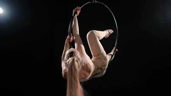 Slim Flexible Young Woman Lying on Side on Air Hoop Rehearsing Split at Black Background with