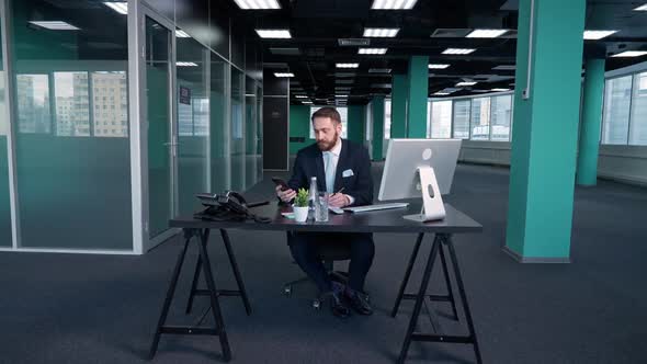 Working Overtime Young Businessman Sits at a Desk in the Office and Works on a Pc Manager Works on