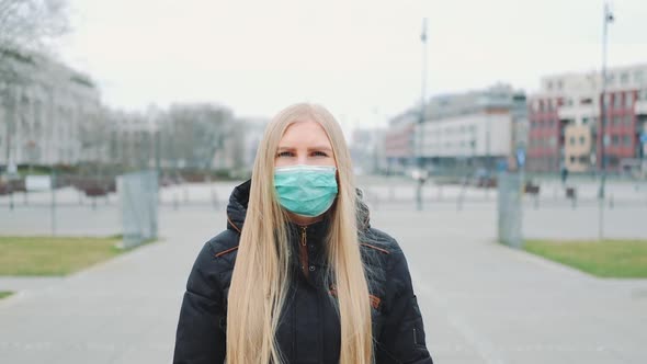 Coronavirus Pandemic: Blonde Woman in a Medical Mask Walking Down the Street
