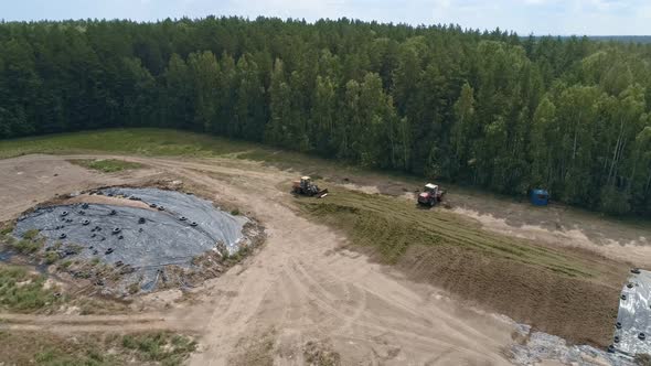 Aerial view of tractors tamp the silage in the Silo Trench next to the forest 11