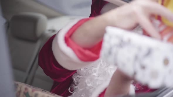 Bearded Santa Giving Present Boxes To Unrecognizable Child From the Car Window. Old Santa Claus