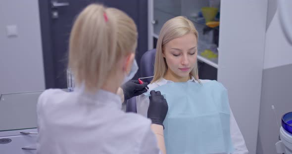 Dentist Doctor Puts a Napkin on a Client Preparing for an Examination