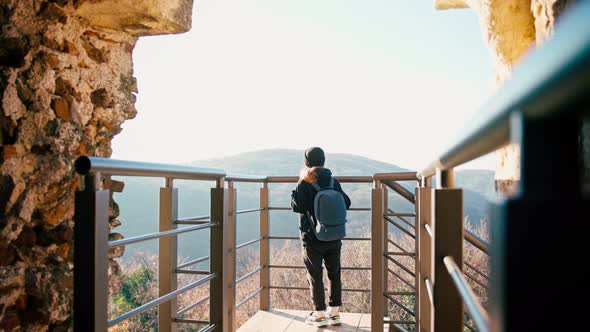 A Young Woman with a Backpack Standing on Observation Deck Enjoying the Top View