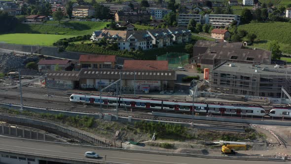 Aerial of train leaving station in a small Swiss town