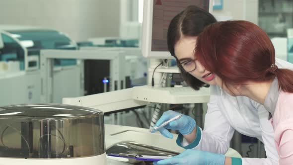 Two Female Biologists Making Notes While Conducting Experiments