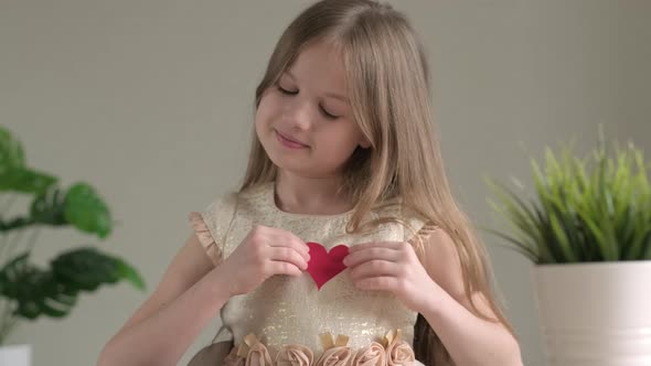Cute Little Girl Holds Small Red Paper Heart and Represents the Heartbeat on Valentines Day