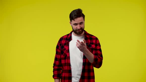 A Confident Smiling Man on a Yellow Background Waves His Hand in Greeting to Someone Doing Coming