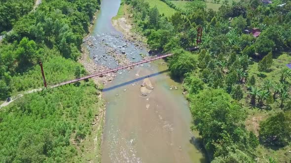 Flycam Moves Over Long Bridge Among Plants Against Sky