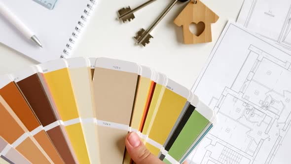 Hands Choosing Colors of Interior Design From the Color Guide