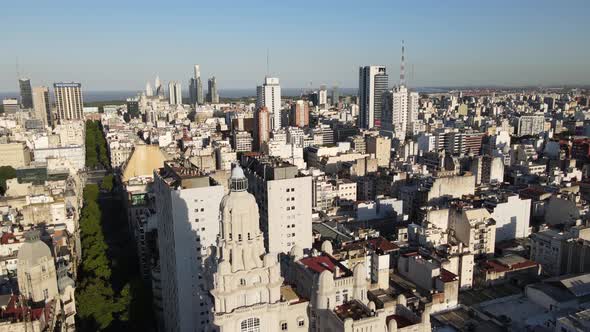 Aerial lowering on Barolo Palace tower in tree-lined May Avenue surrounded by Buenos Aires buildings