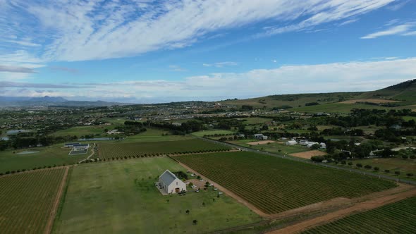 White farm house surrounded by green vineyard in Cape Winelands South Africa, aerial
