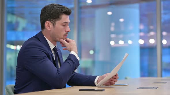 Businessman Reading Documents Doing Paperwork in Office