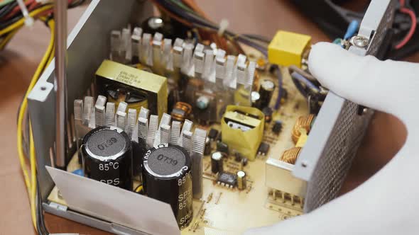 Close Up of a Service Worker Disassembles a PC Power Supply for Cleaning