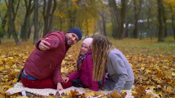 Positive Family Taking Selfie on Cellphone in Autumn