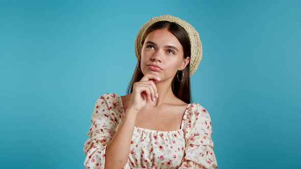 Portrait of Young Thinking Pondering Woman in Hat Having Idea Moment Pointing Finger Up on Blue