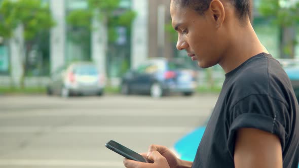 Young Man Standing on the Street Using Smartphone