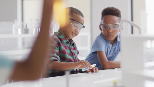 Video of happy african american boys wearing glasses during chemistry lesson