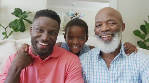 Portrait of happy african american grandfather with adult son and granddaughter