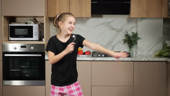 Girl Imitates Singing with Spoon As Microphone in Kitchen