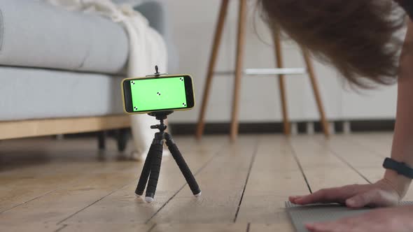 Young Woman Doing the Home Fitness Exercises. Green Screen and Marks on her Phone.