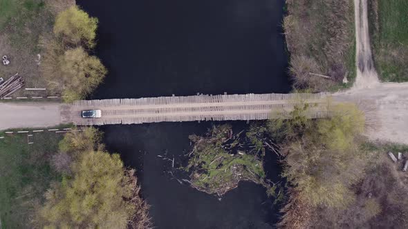 Top View Car Driving Across the River on a Wooden Bridge