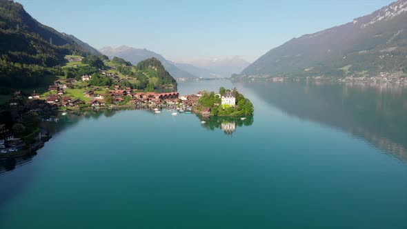 Droneview to famous village Iseltwald, Switzerland with the castle Seeburg. Early morning light with