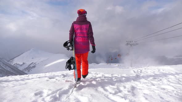 Girl with Snowboard Sitting on Top and Enjoying Mountain Landscape, Sport Woman in Snowy Mountains