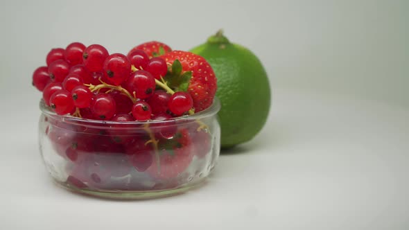 Red Cherries and Strawberries Fruit Inside The Small Transparent Bowl With Lime Outside Rotating Clo