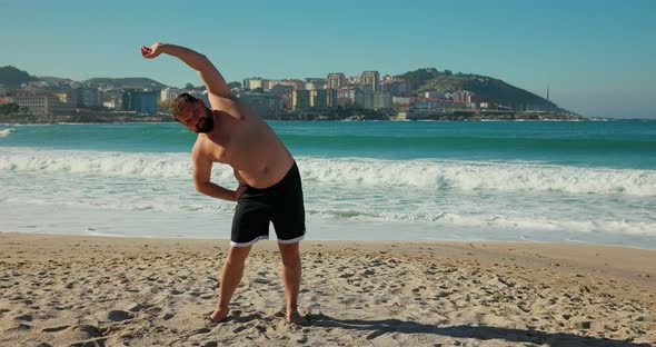 A Man Stretches on the Beach Before a Workout